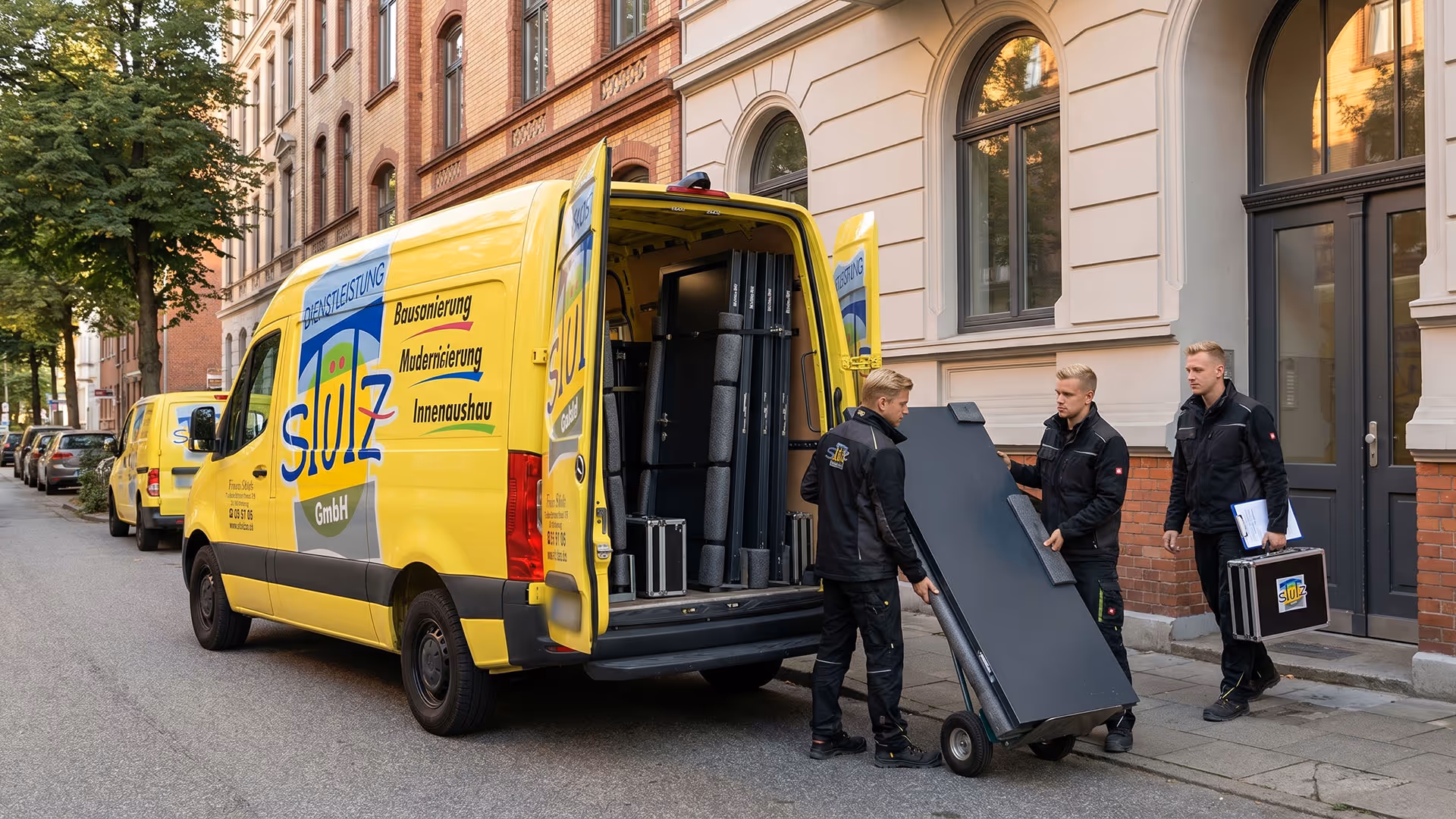 Drei Männer in schwarzer Arbeitskleidung laden Ausrüstung aus einem gelben Firmenwagen in einer Stadtstraße.