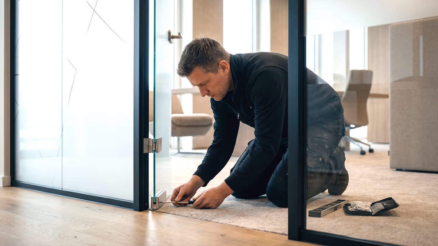 Handwerker montiert eine Glastür in einem modernen Bürogebäude.