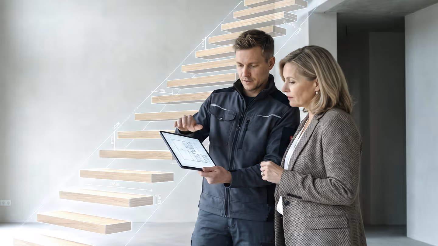 Handwerker erklärt Frau Baupläne auf Tablet vor einer schwebenden Treppe mit technischen Maßen.