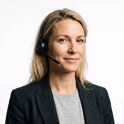 Frau mit Headset, die freundlich lächelt, in grauem Shirt und schwarzem Blazer.