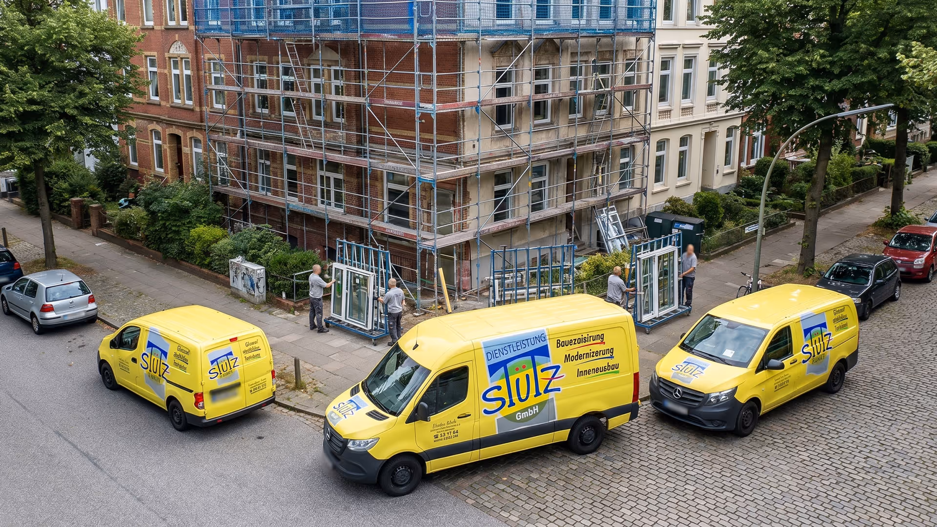 Drei gelbe Stütz GmbH-Firmenfahrzeuge vor einem mit Gerüst eingedeckten Wohnhaus im Umbau.
